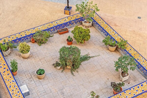 Un patio con suelo de baldosas y una variedad de plantas en macetas dispuestas en un diseño.