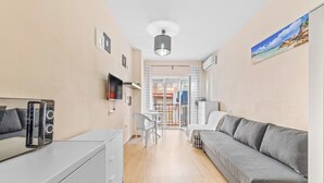 Una sala de estar moderna con un sofá gris, un televisor montado en la pared y un comedor con mesa y sillas.