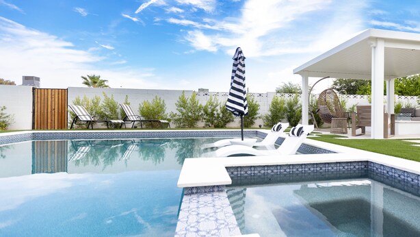 Una piscina con lettini e un'area relax coperta.