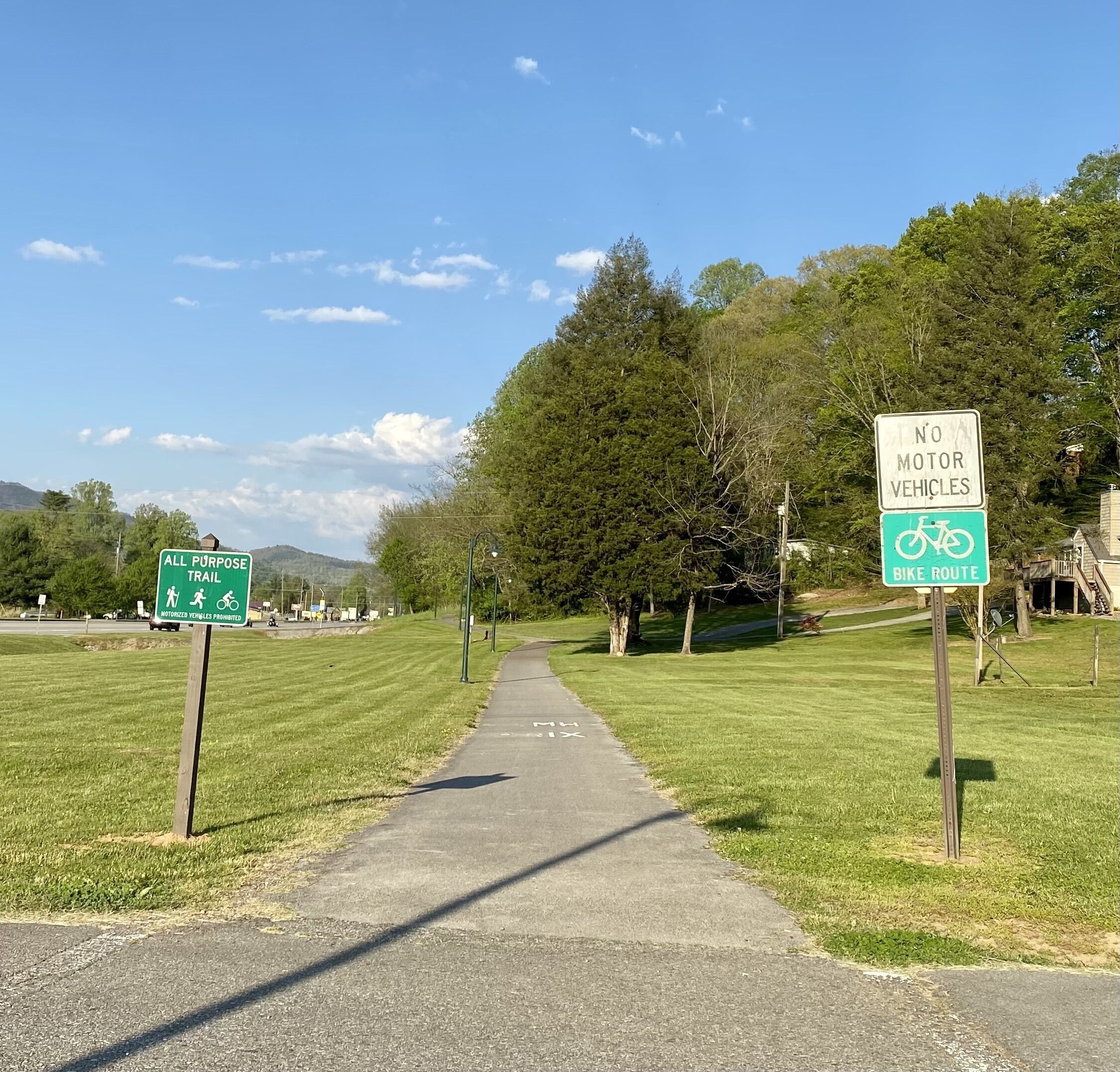 A paved path with signs indicating a bike route and a no motor vehicles area.