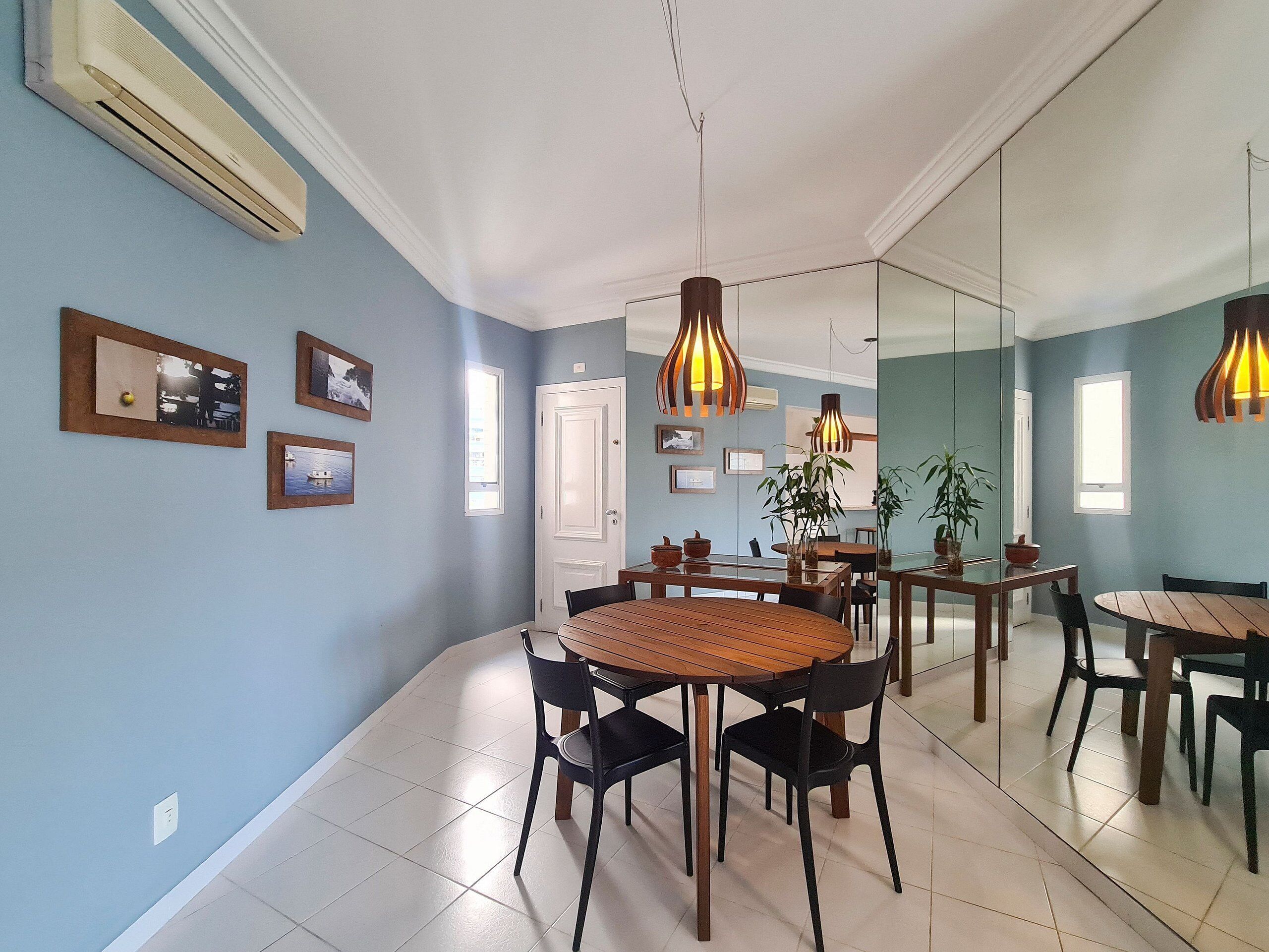A dining area with a round wooden table, black chairs, and hanging pendant lights.