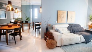 Una sala de estar moderna con sofá, mesa de comedor, sillas e iluminación colgante.