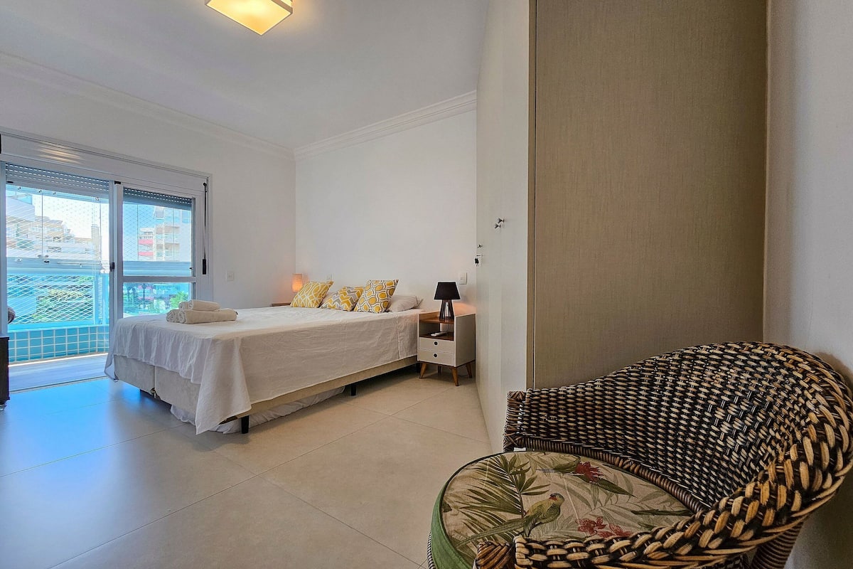 Un dormitorio con cama, mesita de noche y una silla de mimbre.