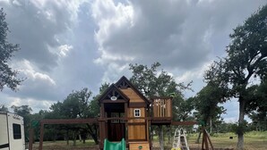 Un parque infantil con tobogán, muro de escalar y columpios.