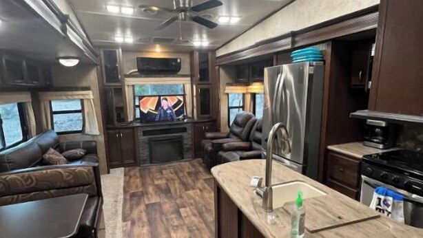 Interior compacto de autocaravana con kitchenette, zona de estar y ventilador de techo.