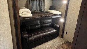 Un cuarto pequeño y cerrado con una cama nido y un sofá.