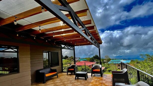 An outdoor patio with a view of the ocean, featuring a covered seating area with chairs and a bench, and a patterned floor. - Moni's House, Terraza con Espectacular Vista al Mar, (Monteverde)