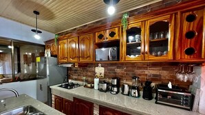 A kitchen with wooden cabinets, a granite countertop, and various appliances. - Moni's House, Terraza con Espectacular Vista al Mar, (Monteverde)