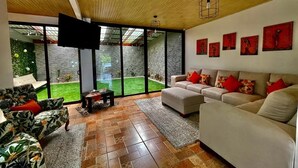 A spacious living room with a large sofa set, a coffee table, and a flat-screen TV mounted on the wall. - Moni's House, Terraza con Espectacular Vista al Mar, (Monteverde)