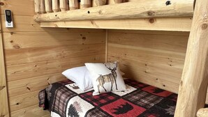 Una cama individual superpuesta con cabecera de madera y colcha acolchada con estampados de animales.