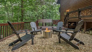 Uma área externa com assentos Adirondack, lareira e deck de madeira.