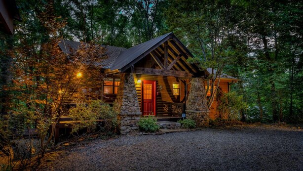 A rustic cabin with a stone exterior, a red door, and a wooden porch. - Away to the Lake - Lake Blue Ridge dock | Hot Tub Pool Table | Ping Pong | Fire pit (Blue Ridge)