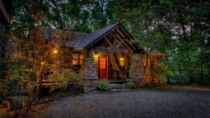 Un rustico chalet con facciata in pietra, una porta rossa e un portico in legno.