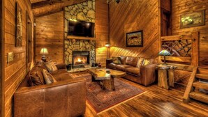 A cozy log cabin interior with a stone fireplace, leather furniture, and rustic decor. - Away to the Lake - Lake Blue Ridge dock | Hot Tub Pool Table | Ping Pong | Fire pit (Blue Ridge)