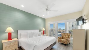 A bedroom with a bed, nightstands, a chair, and a TV. - 🤗 E11G=Awesome! 6BR Beachview. Htd Pools. Easy beach access! (Gulf Shores)
