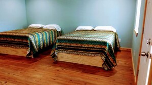 Une chambre avec deux lits, un plancher en bois et des murs de couleur turquoise.