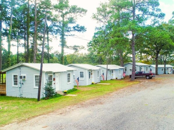 A row of small, single-story cabins with a gravel driveway, surrounded by trees. - Bullfrog Marina RV Park and Cabins (Jefferson)