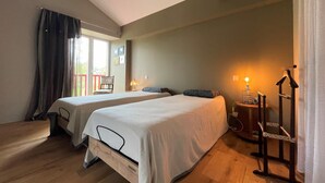 A bedroom with two beds, wooden flooring, a chandelier, and a small table with a lamp. - Eiherabidia - Beyrie SUR Joyeuse (BEYRIE SUR JOYEUSE)