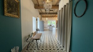 A hallway with a patterned floor, a table with chairs, a chandelier, and a framed picture on the wall. - Eiherabidia - Beyrie SUR Joyeuse (BEYRIE SUR JOYEUSE)