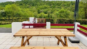 A wooden picnic table with a metal railing and a view of a lush green landscape. - Eiherabidia - Beyrie SUR Joyeuse (BEYRIE SUR JOYEUSE)