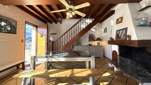 A spacious living area with a wooden ceiling, a fireplace, a dining table, and a staircase leading to an upper level. - LE Cailhabas - Lescun (LESCUN)