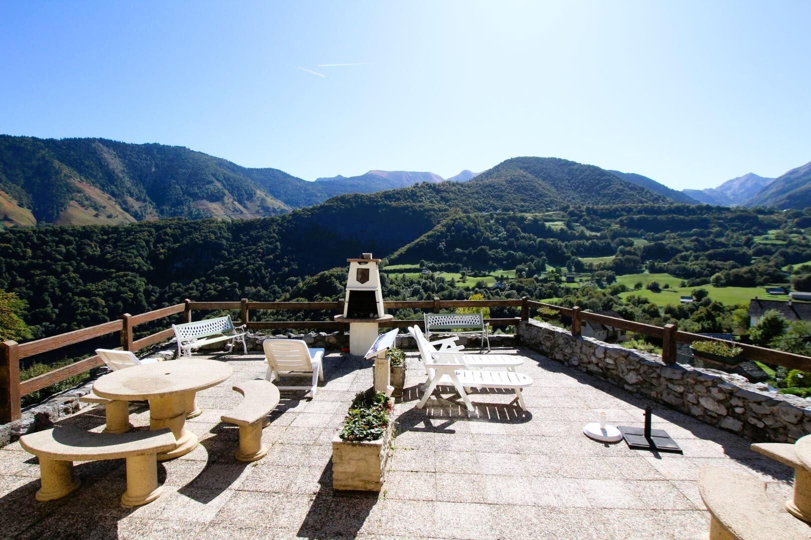 An outdoor patio with stone tables and chairs, a barbecue grill, and a stone wall.