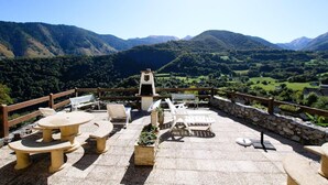 An outdoor patio with stone tables and chairs, a barbecue grill, and a stone wall. - LE Cailhabas - Lescun (LESCUN)