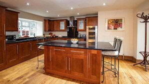 Una cocina amplia con armarios de madera, una isla grande y una zona de comedor con sillas.
