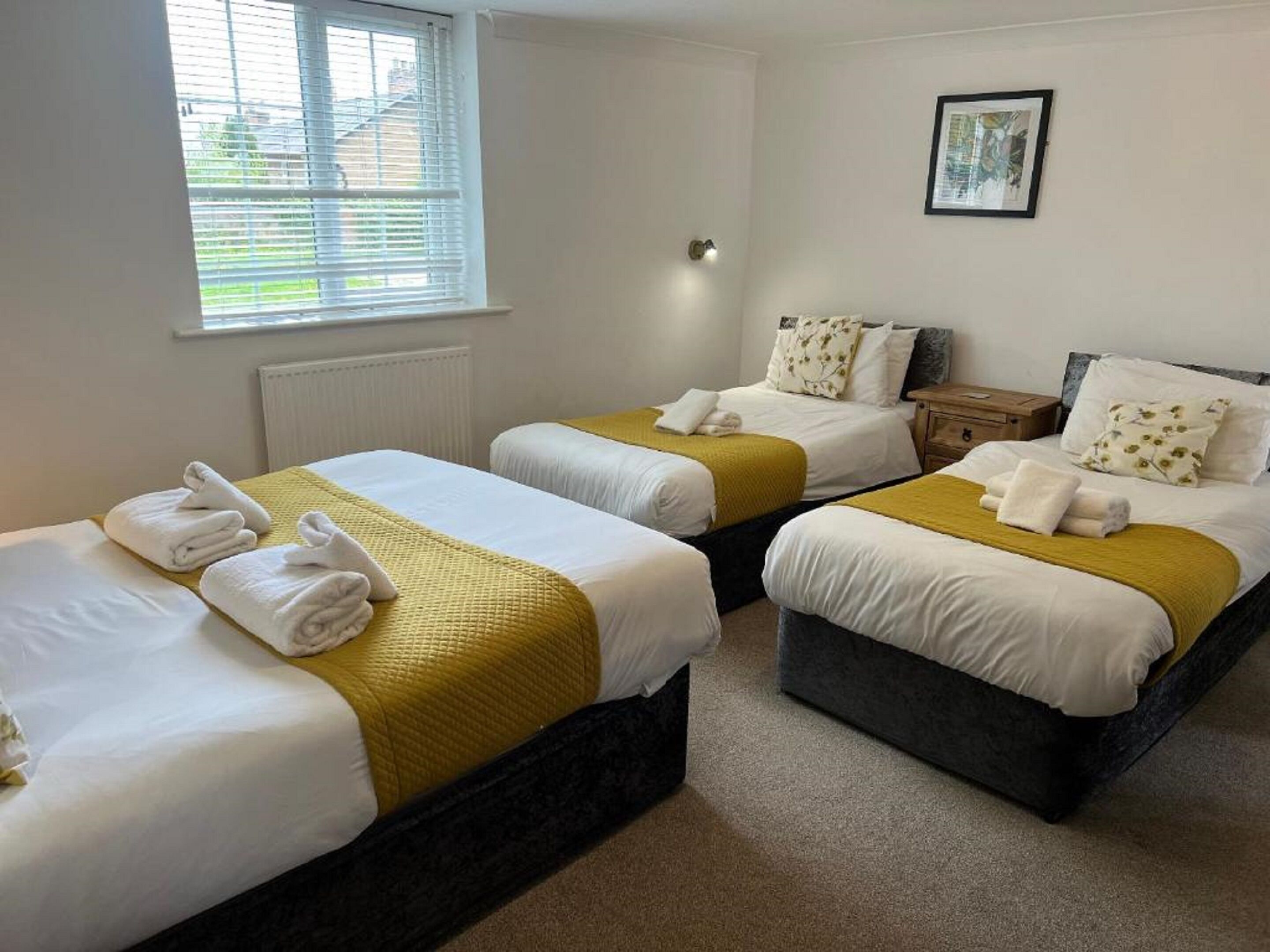Une chambre d’hôtel avec deux lits simples, chacun étant équipé d’une couverture jaune et de serviettes blanches.