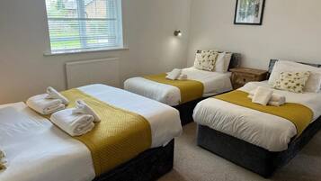 Une chambre d’hôtel avec deux lits simples, chacun étant équipé d’une couverture jaune et de serviettes blanches.