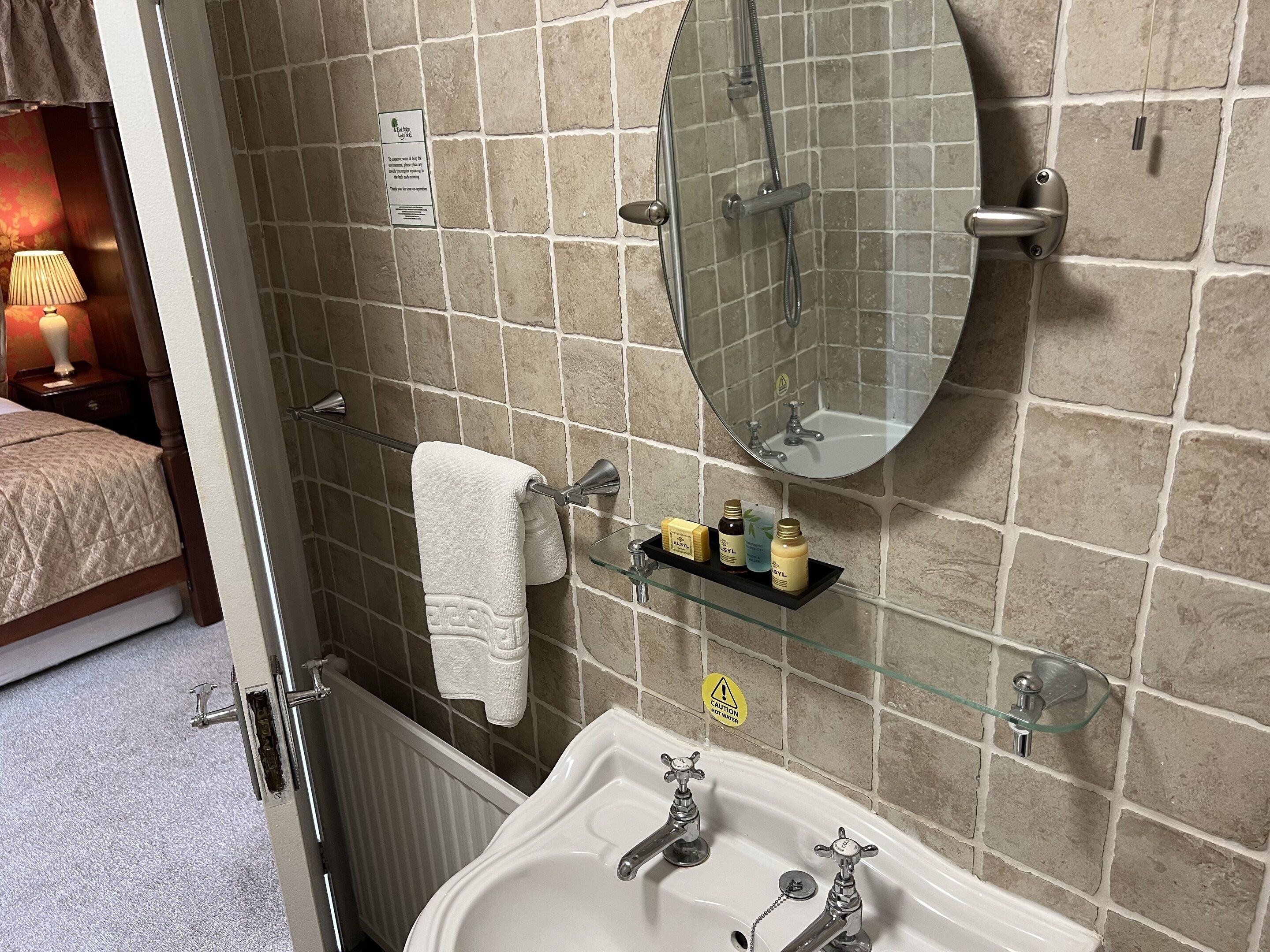 A bathroom with a shower, sink, and a glass shelf with toiletries.