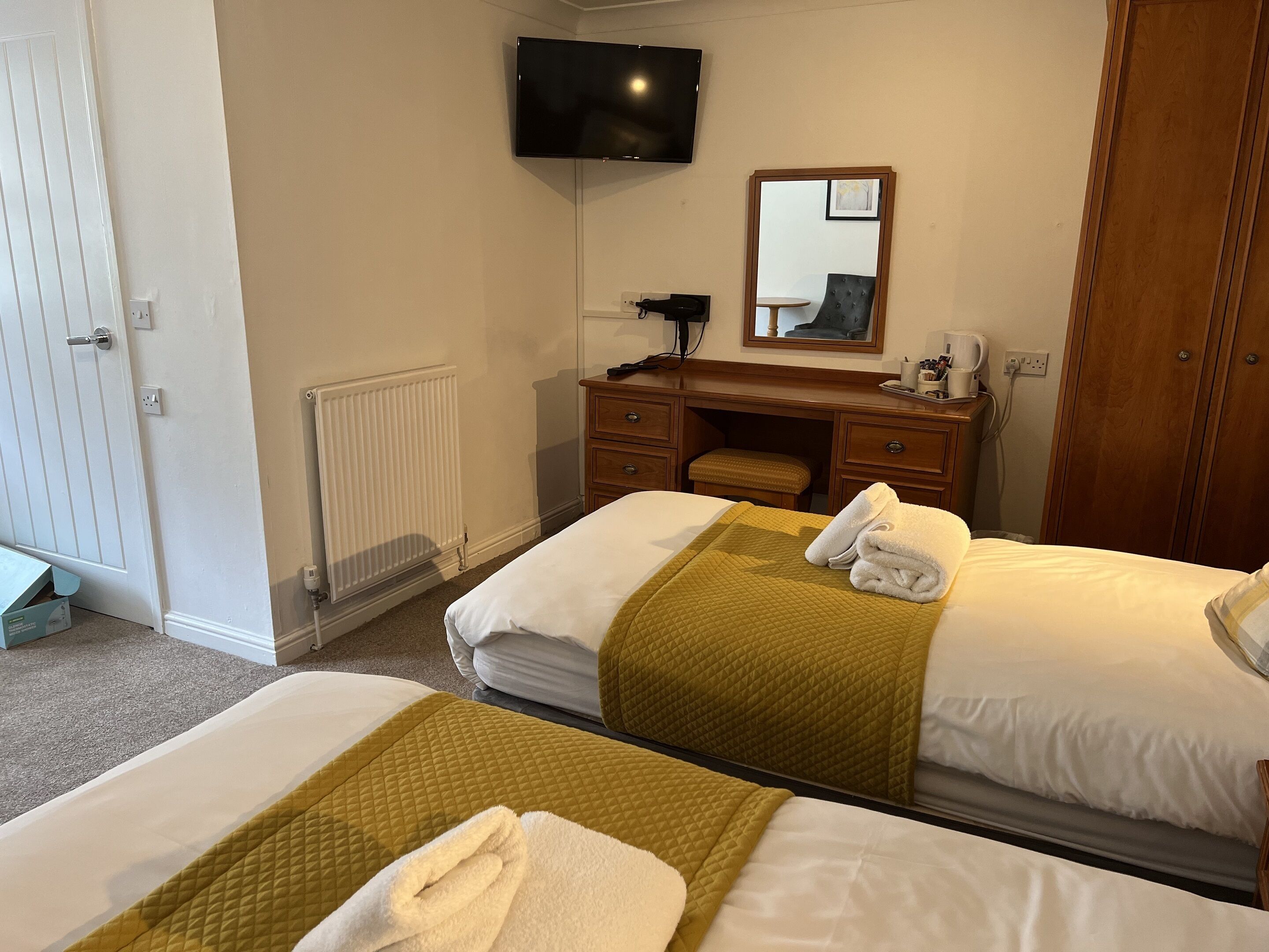 A hotel room with two beds, a desk, a chair, a television, and a wardrobe.