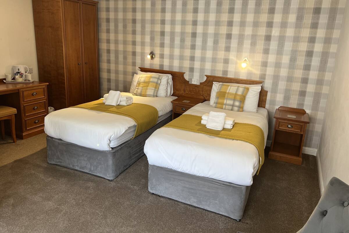 A hotel room with two beds, a wardrobe, a desk, and a nightstand.