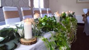 Una mesa decorada con mantel blanco, velas y follaje.