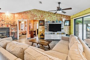 Relax in a stylish living area with a sofa set, flat-screen TV, and ceiling fan.
