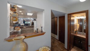 Un couloir avec un coin cuisine, des portes en bois et un miroir avec une serviette.