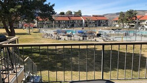A view of a pool area with multiple pools and a building with red roofs in the background. - Crescent Bar Unit 102 (Quincy)