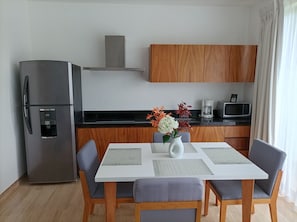 Una cocina moderna con un refrigerador de acero inoxidable, gabinetes de madera, un microondas y una cafetera.