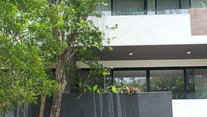 A modern building with large windows, a tree in front, and a sign with the text "Great news!" - AC 1BR (Tulum)