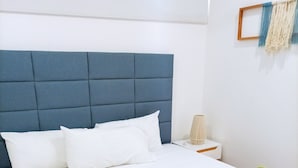 A neatly made bed with white linens and a blue headboard. - AC 1BR (Tulum)