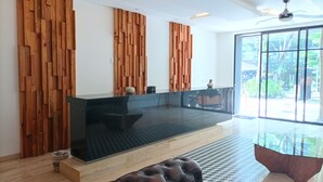 A modern interior with a wooden wall panel, a black reception desk, and a glass partition. - AC 1BR (Tulum)