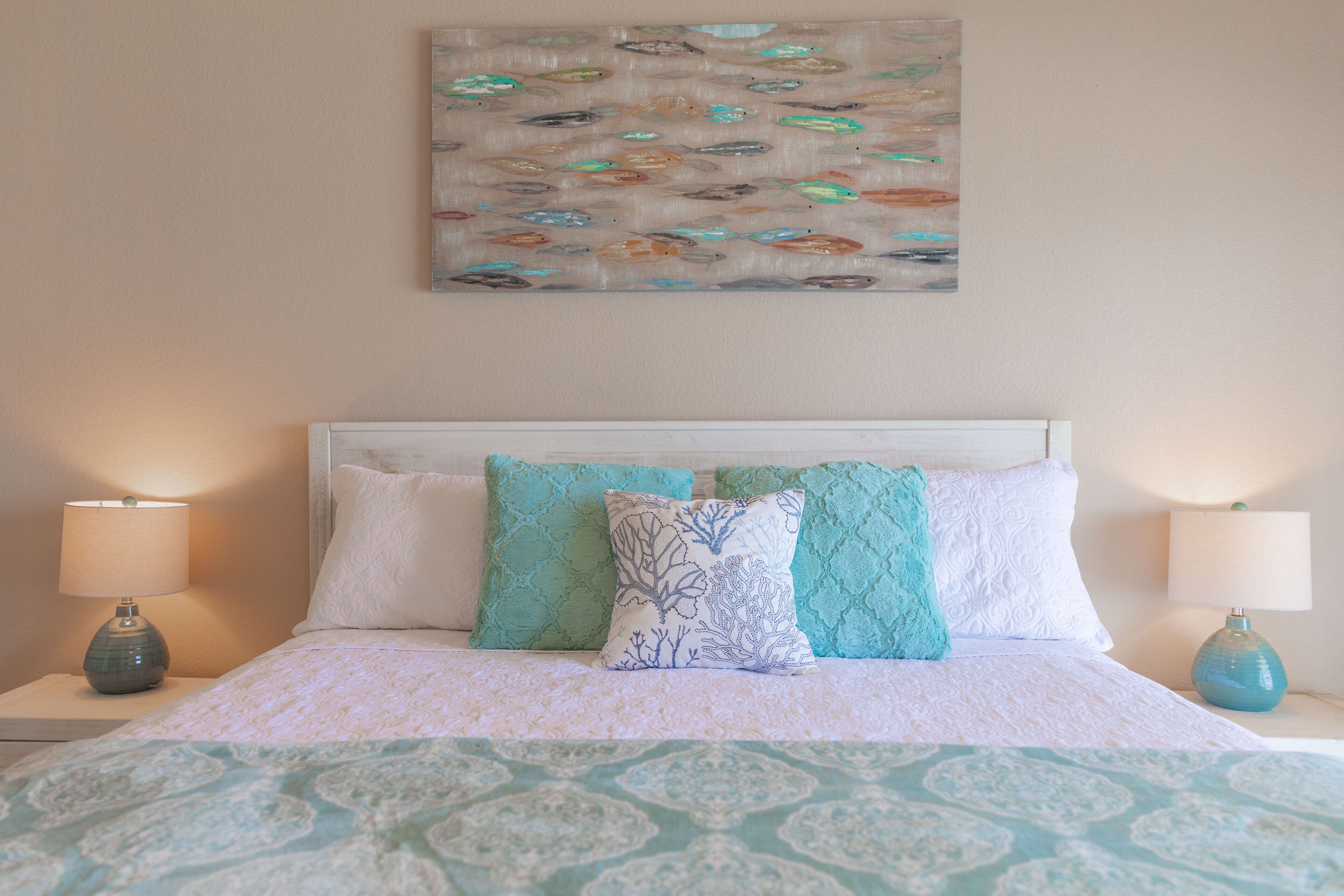 A bed with a patterned bedspread, two matching lamps, and decorative pillows.