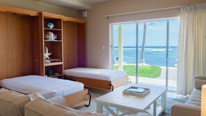 Una habitación con dos camas, un sofá, una mesa y vista al océano.