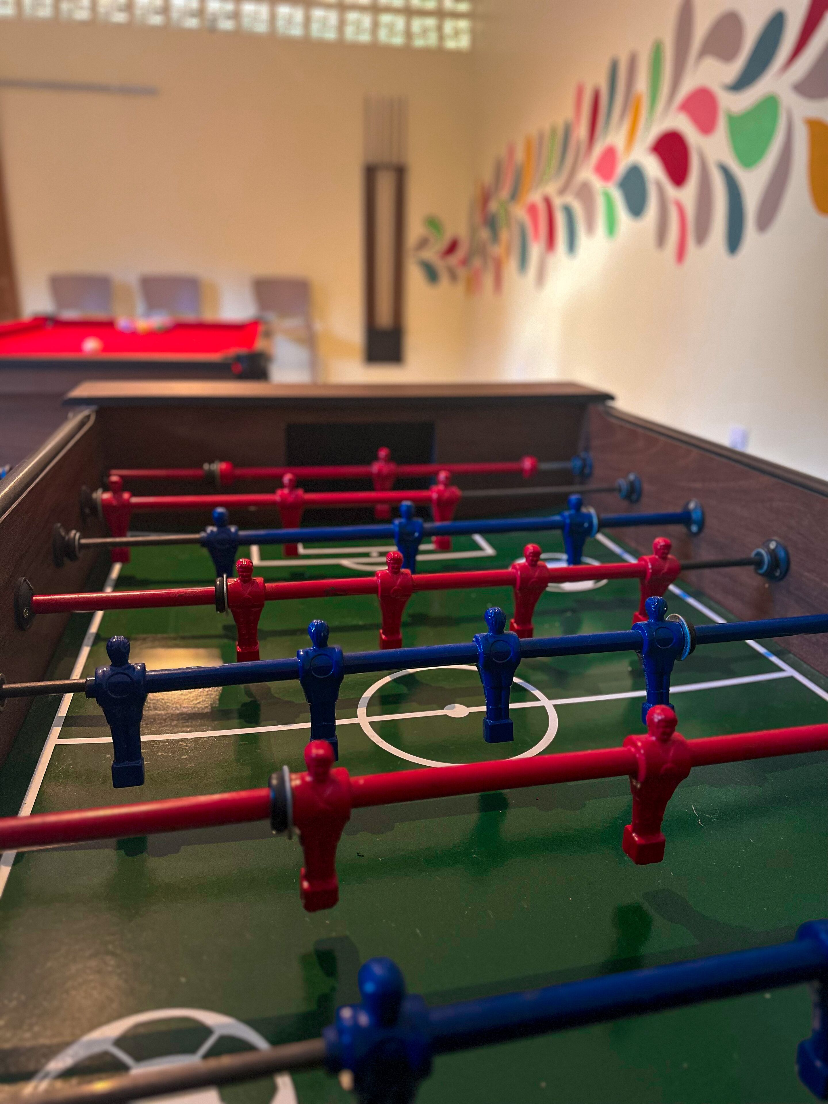 Una mesa de fútbol de mesa con fichas rojas y azules, sobre un campo verde con marcas blancas.