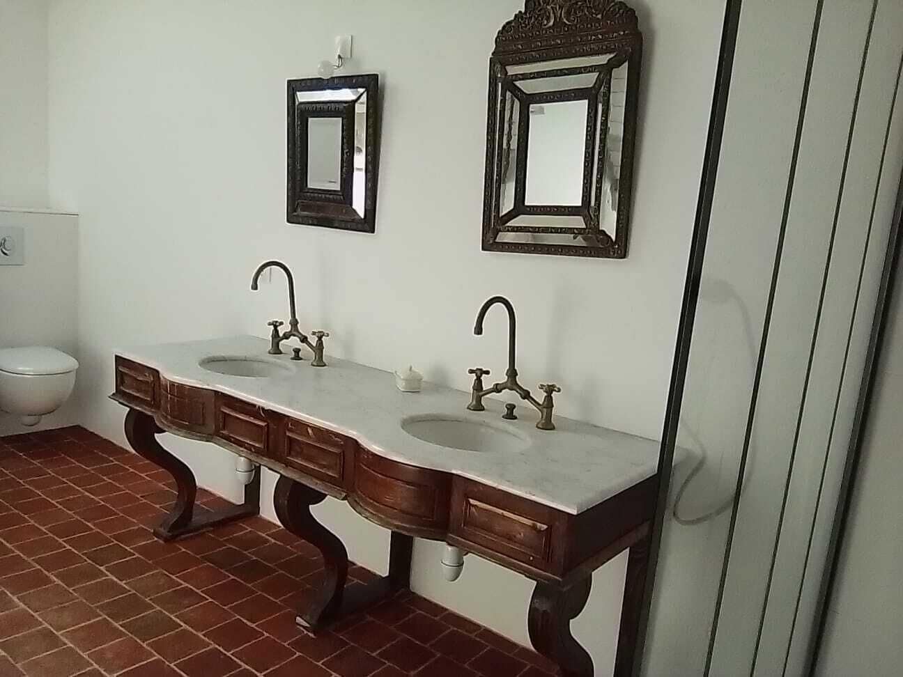 Ein Badezimmer mit einem Doppelwaschbecken, zwei Spiegeln und einer Toilette.
