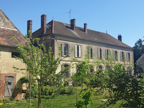 A historic building with multiple chimneys, a brick facade, and a series of windows with shutters.