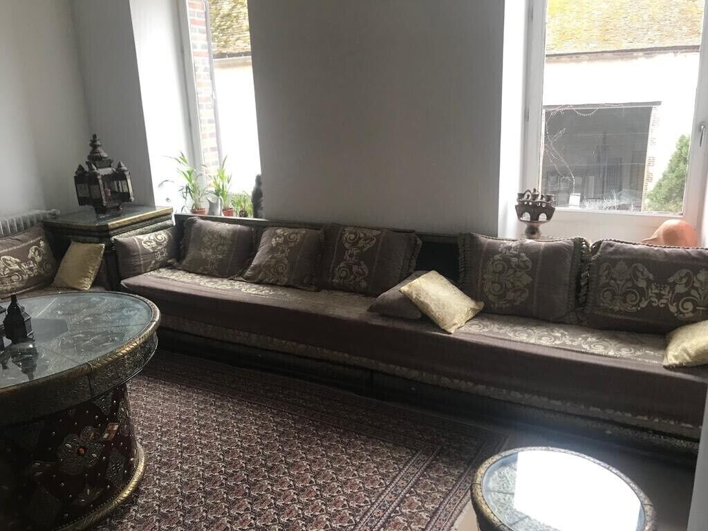 A cozy seating area with a patterned sofa and cushions, a glass coffee table, and a decorative lantern.