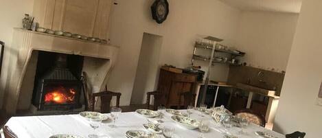 A dining room with a fireplace, a clock on the wall, and a table set for a meal.