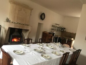 A dining room with a fireplace, a clock on the wall, and a table set for a meal.