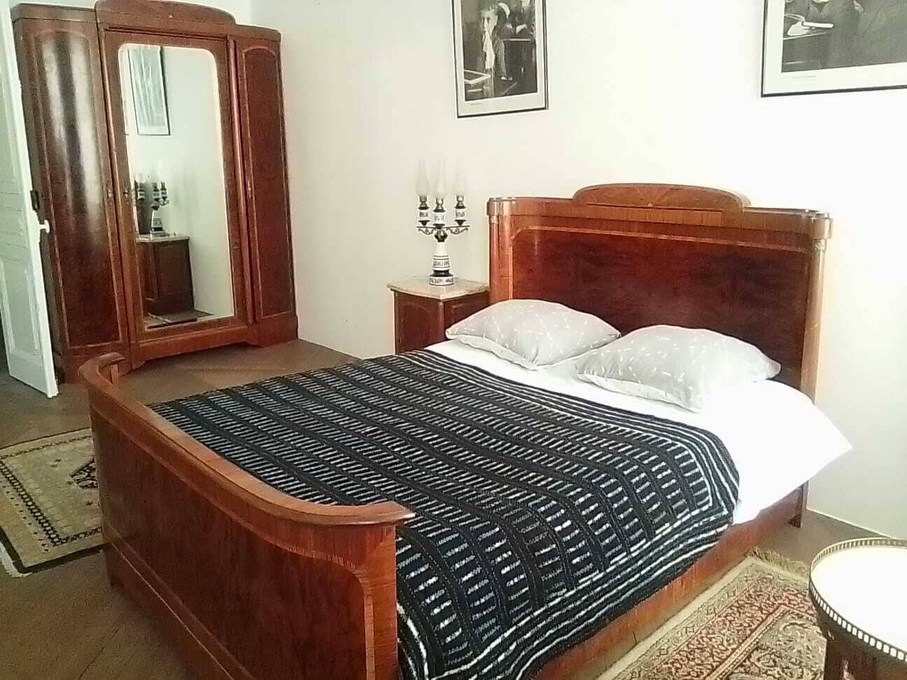Ein Schlafzimmer mit einem hölzernen Bett, einem Nachttisch, einem Spiegel und einem gerahmten Bild an der Wand.
